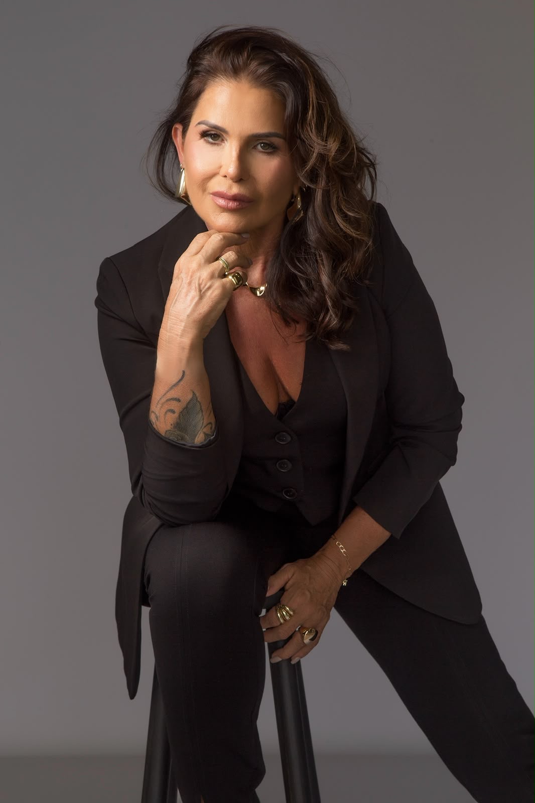 Rita Rostirolla em estúdio, de terno preto